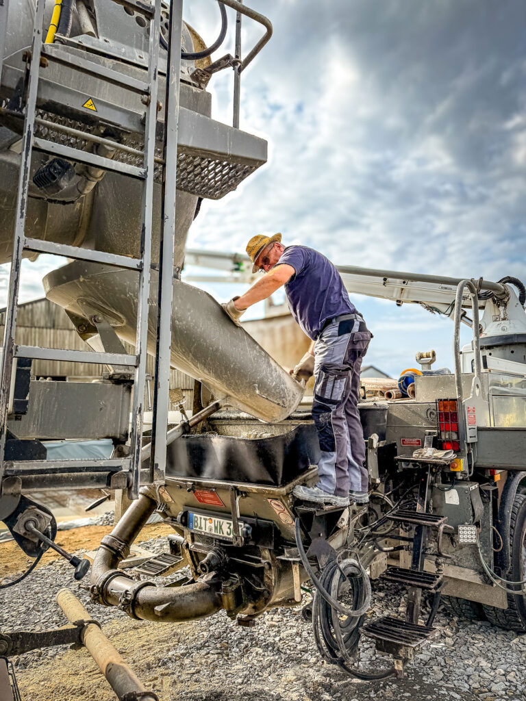 Mischer- und Pumpenfahrer befüllt Betonpumpe auf der Baustelle