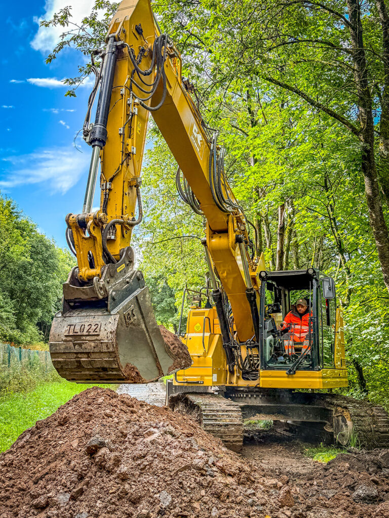 Mitarbeiter steuert einen großen Kettenbagger bei Erdarbeiten
