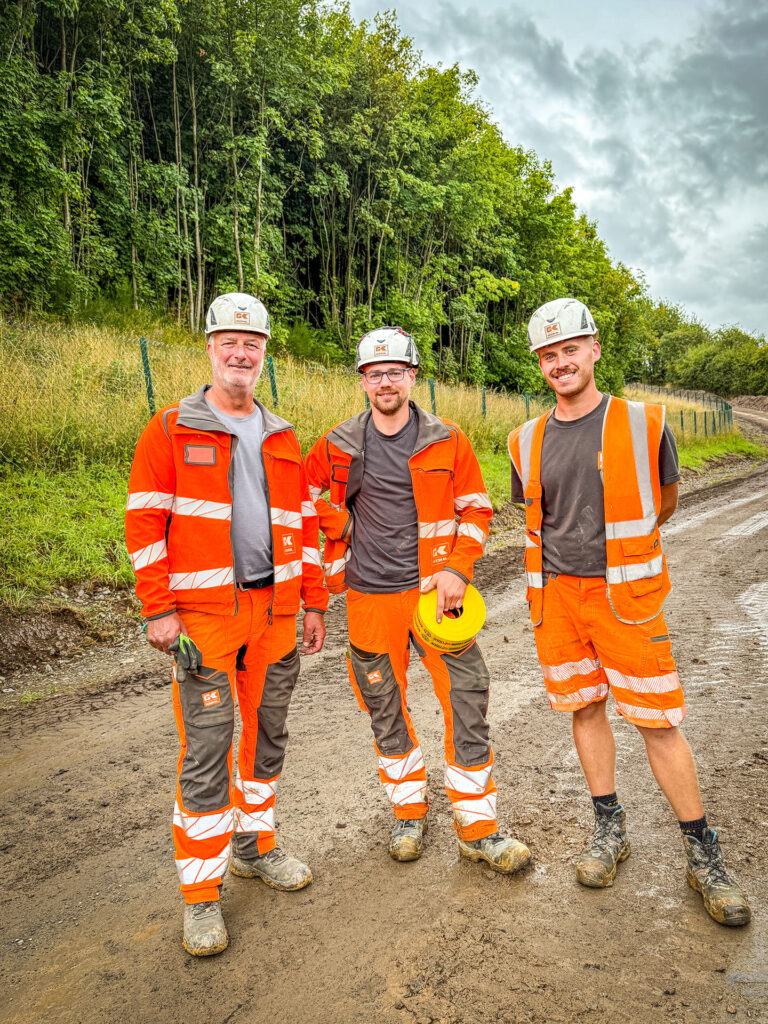 Drei Mitarbeiter im Tiefbau stehen gemeinsam auf einer Baustelle