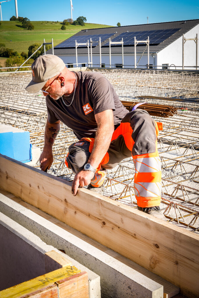 Mitarbeiter richtet Holzelemente auf einer Baustelle aus und überprüft deren Position