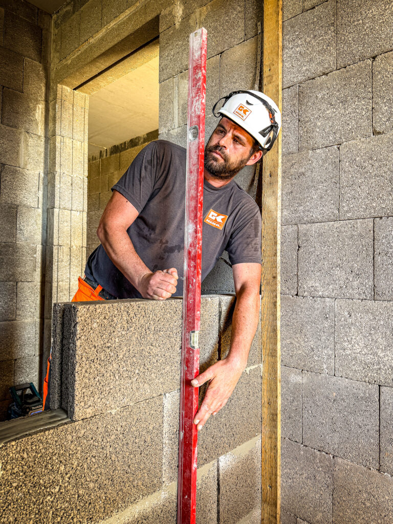 Mitarbeiter richtet eine gemauerte Wand mit einer Wasserwaage auf einer Baustelle aus